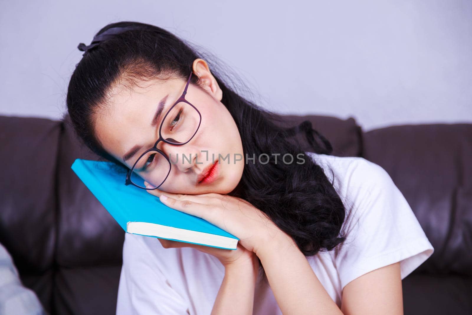 sleepy woman and reading boring book on sofa at home