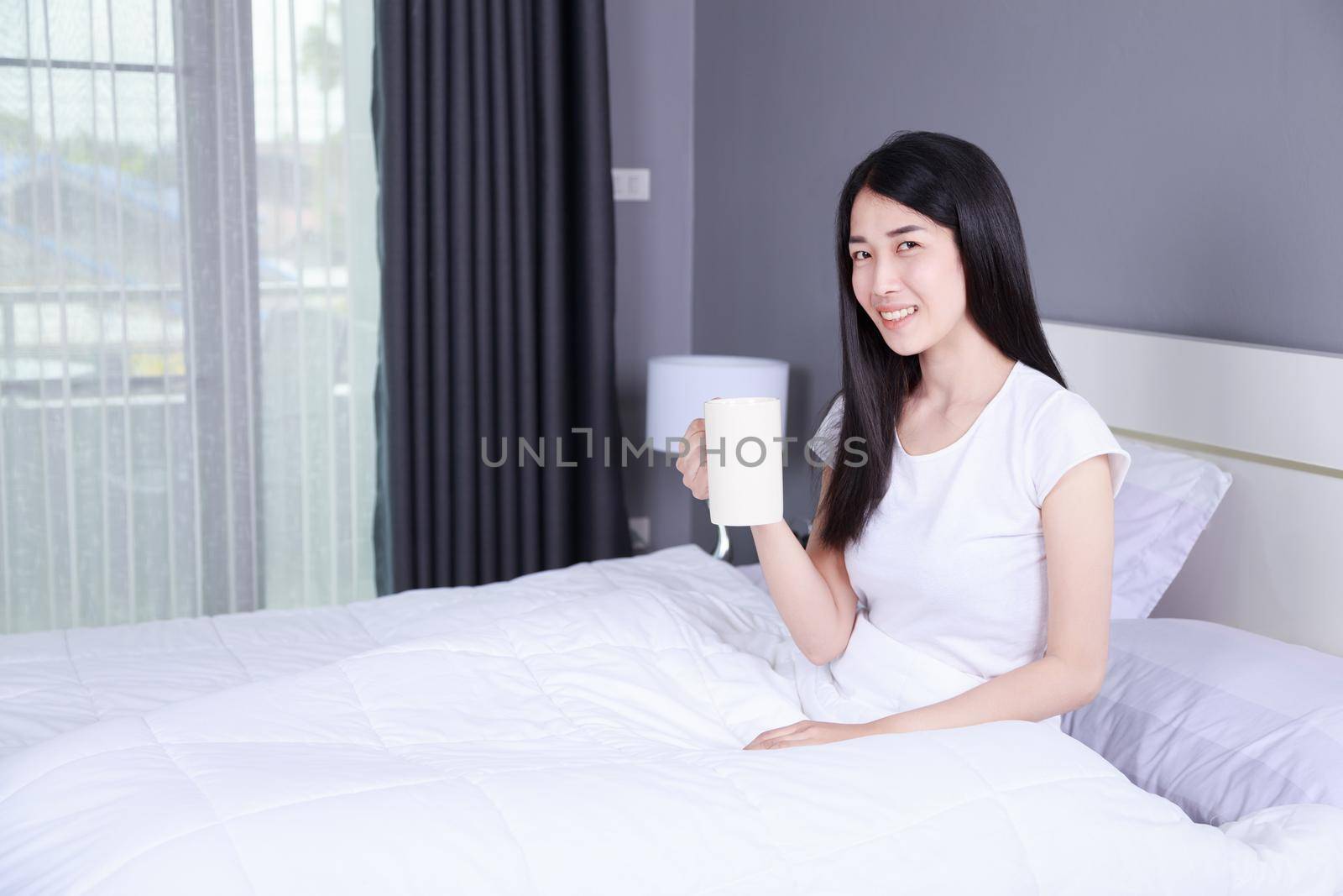 woman on bed with a cup of coffee in the bedroom