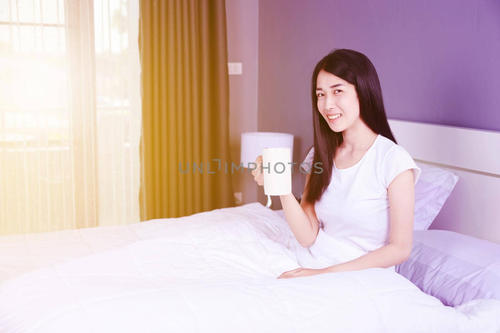 woman on bed with a cup of coffee in the bedroom