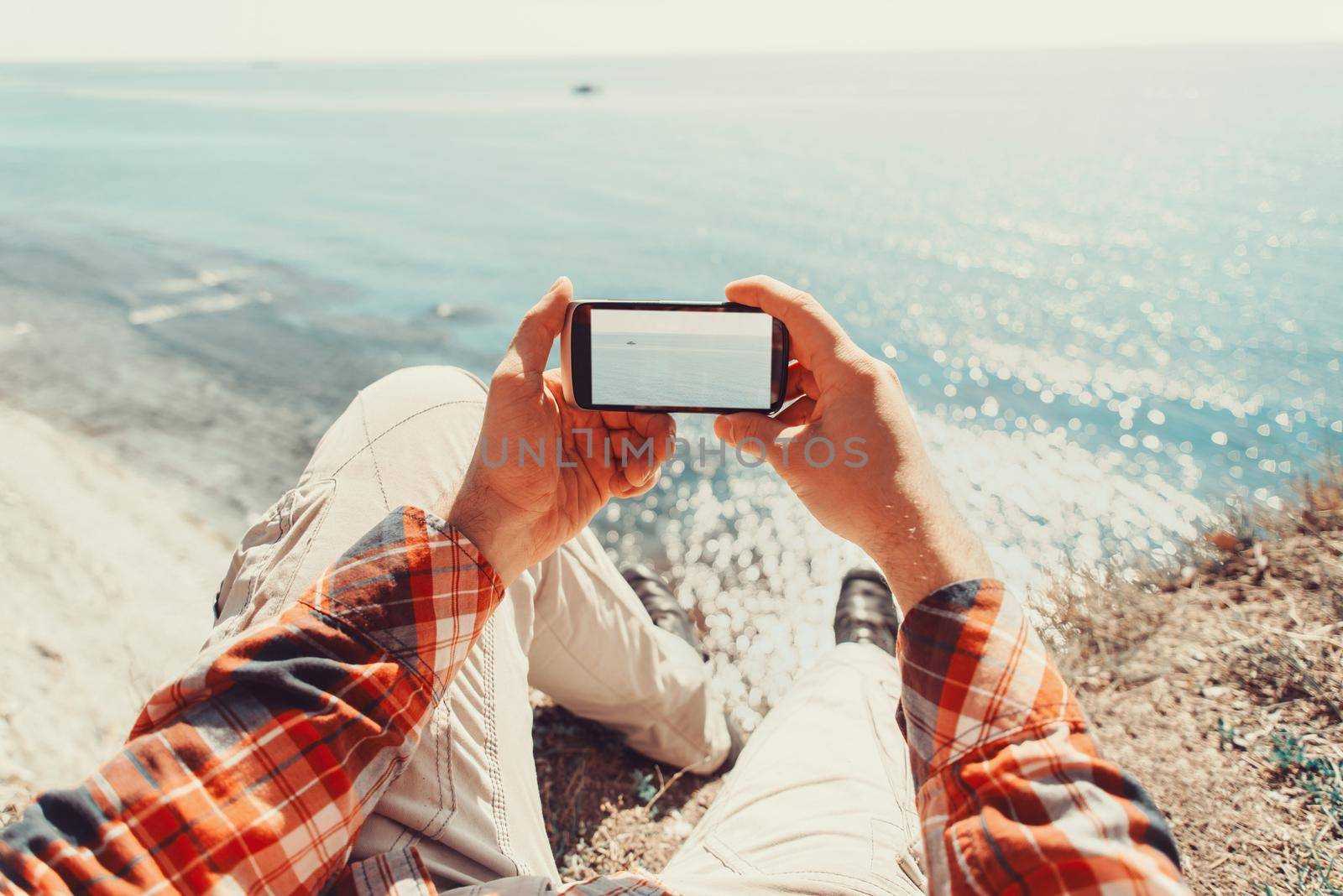 Traveler man taking photographs sea with smartphone. Point of view shot