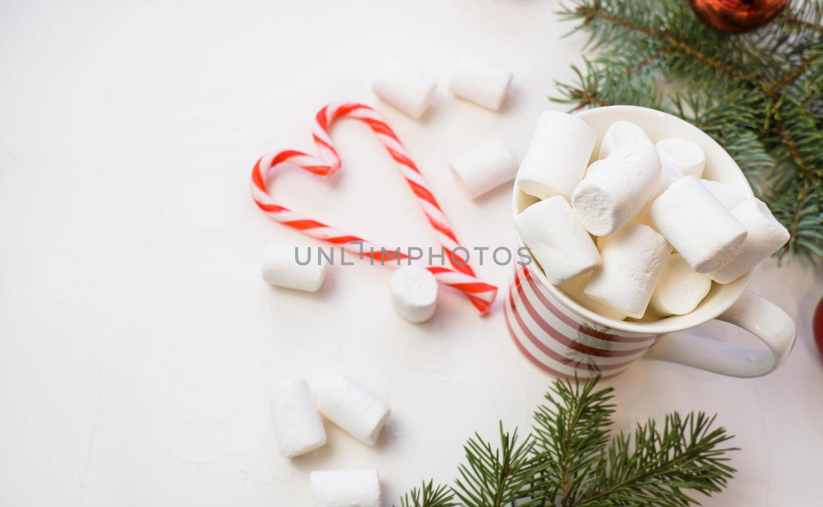 Traditional hot chocolate with marshmallows and lollipops on a white textured background. Christmas drink theme