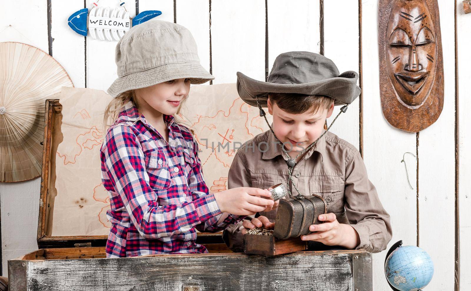 smiling little boy and girl with jewelry sitting in big old chest