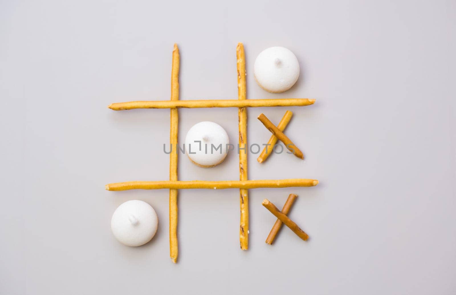 tic-tac-toe from crackers and sticks on a gray background. Food concept. Edible snacks dry sticks with salt and cookies on a white plate. Straws, sticks for crackers