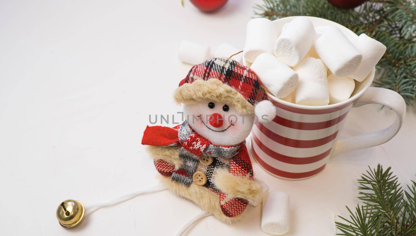 Traditional hot chocolate with marshmallows and a snowman on a white textured background. Christmas drink theme