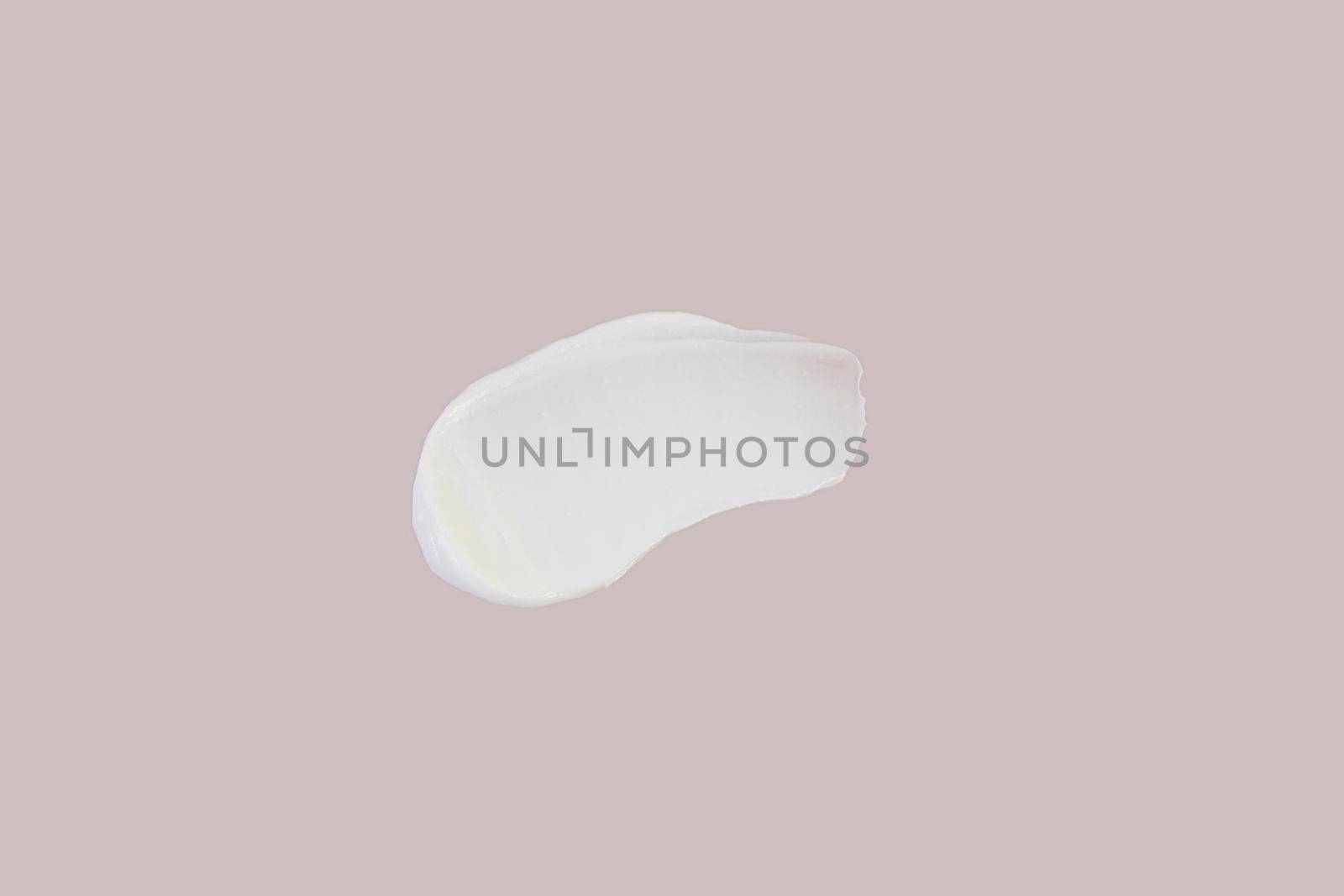 White smear of face cream, on a beige background. Cream texture on beige background.