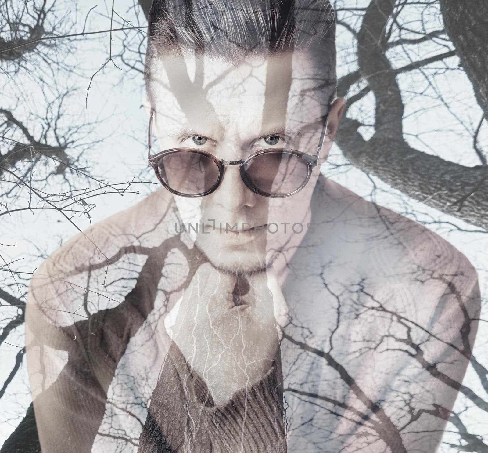 Double exposure portrait of pensive young man combined with image of trees in forest