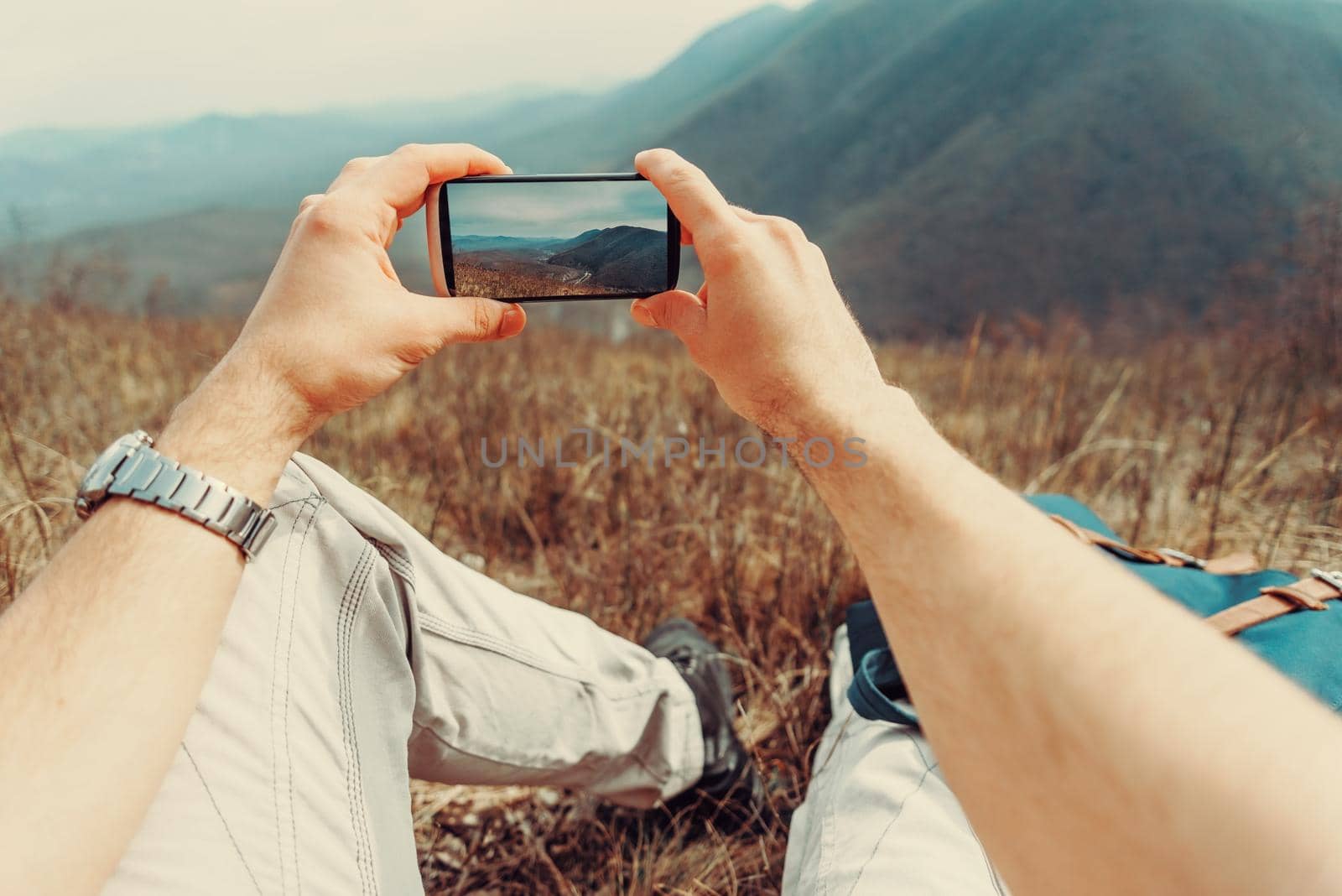 Man taking photographs mountain with smartphone by alexAleksei