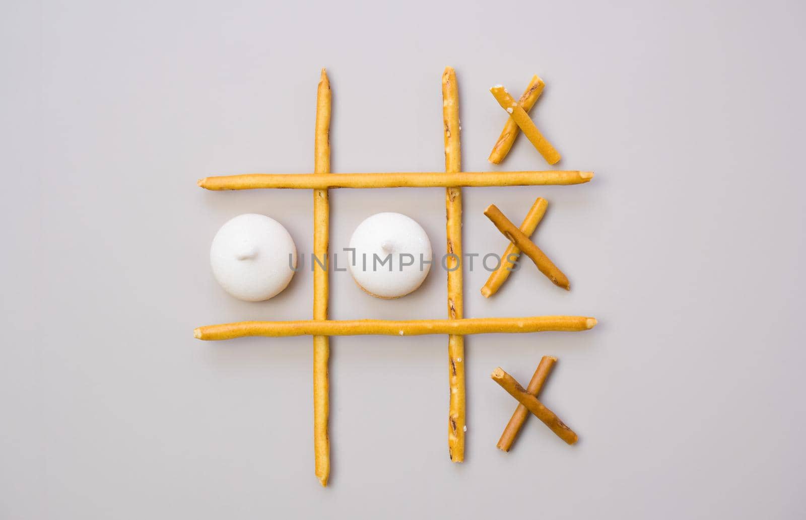 tic-tac-toe from crackers and sticks on a beige background. Food concept. Edible snacks dry sticks with salt and cookies on a white plate. Straws, sticks for crackers. by Ekaterina34