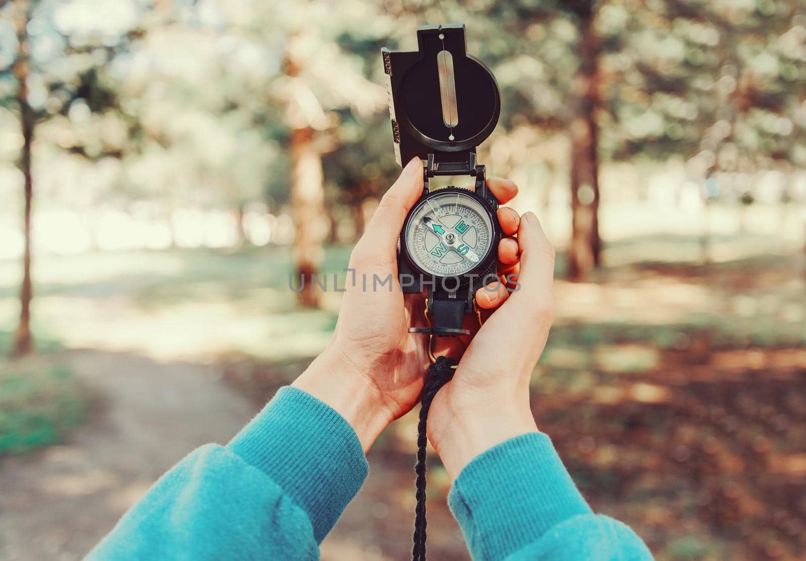 Traveler holding a compass in summer forest by alexAleksei