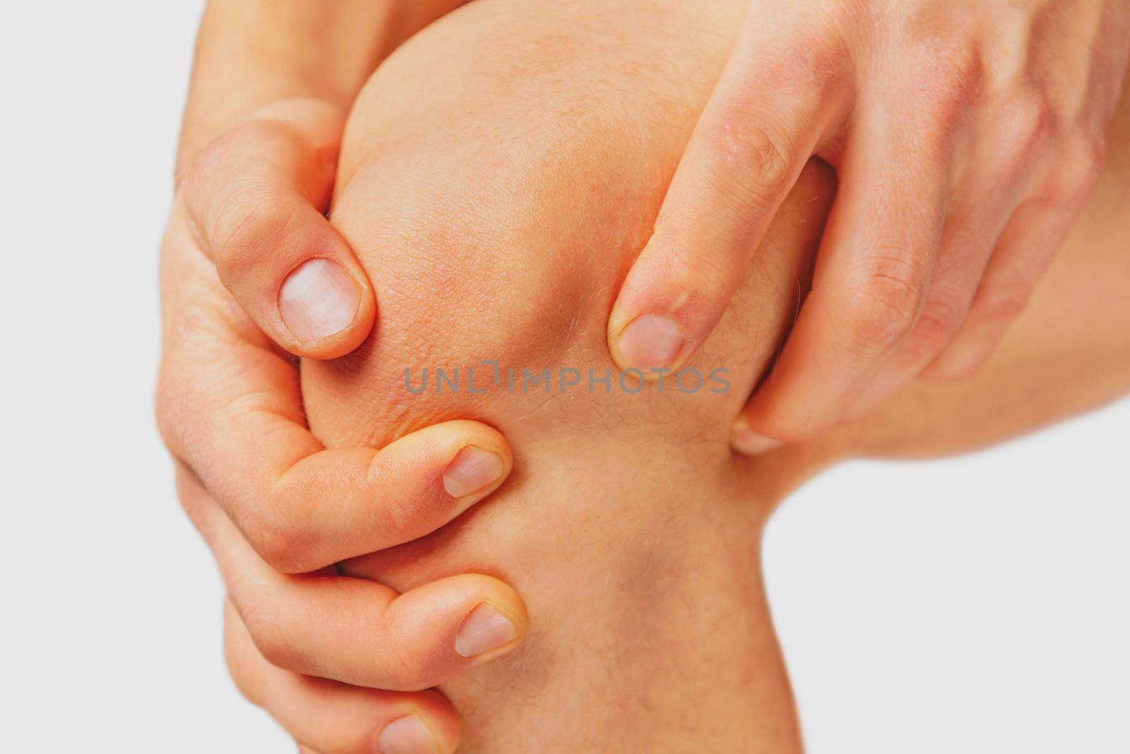 The man is touching the knee joint due to acute pain on a white background