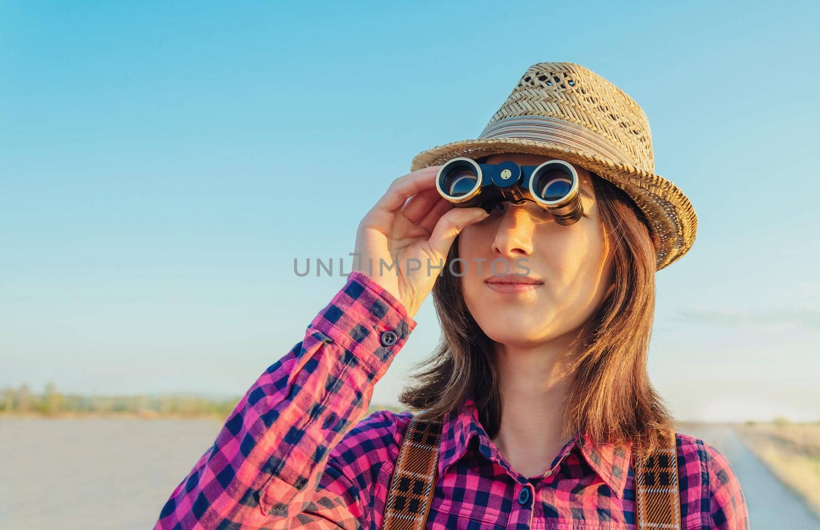 Traveler young woman looking through binoculars outdoor. Space for text in left part of image
