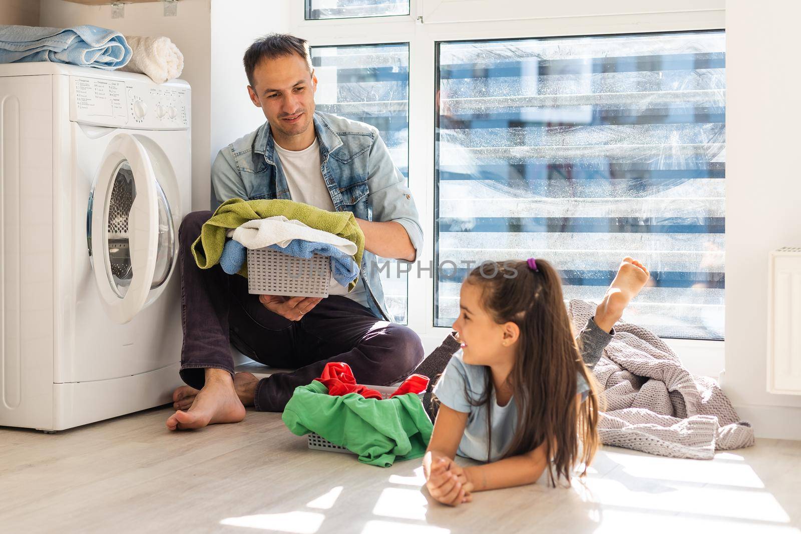 Happy family man father householder and child daughter in laundry with washing machine