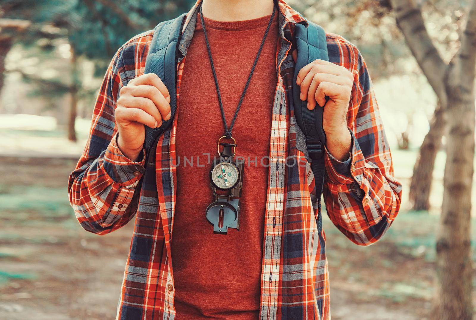 Tourist young man with backpack and compass walking in summer forest