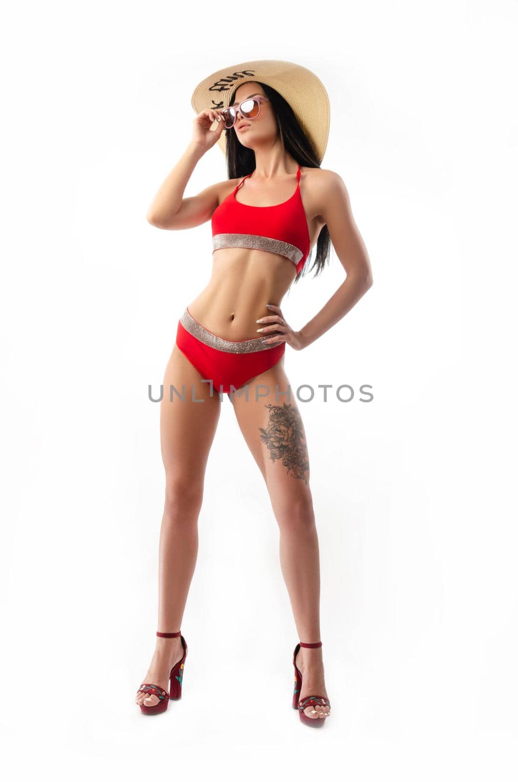 the brunette in a red swimsuit, slim and sexy in a summer hat isolated on a white background