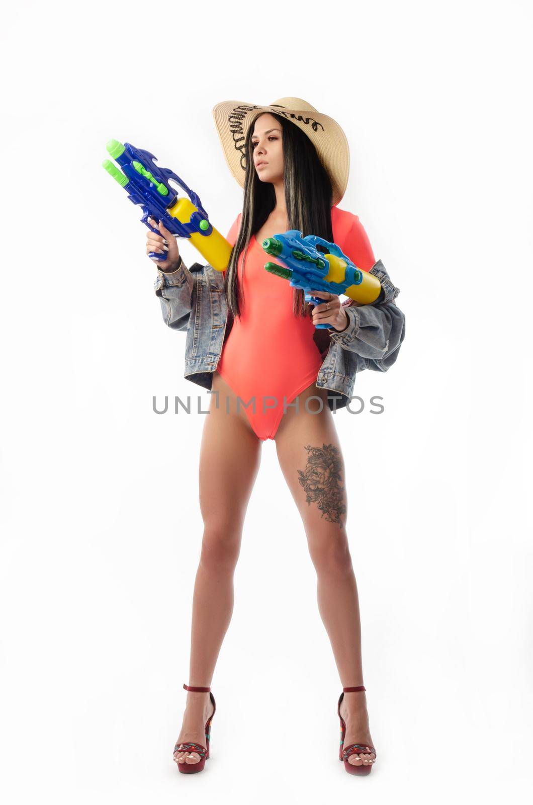 brunette girl with a water gun in summer clothes, slim and sexy isolated on a white background