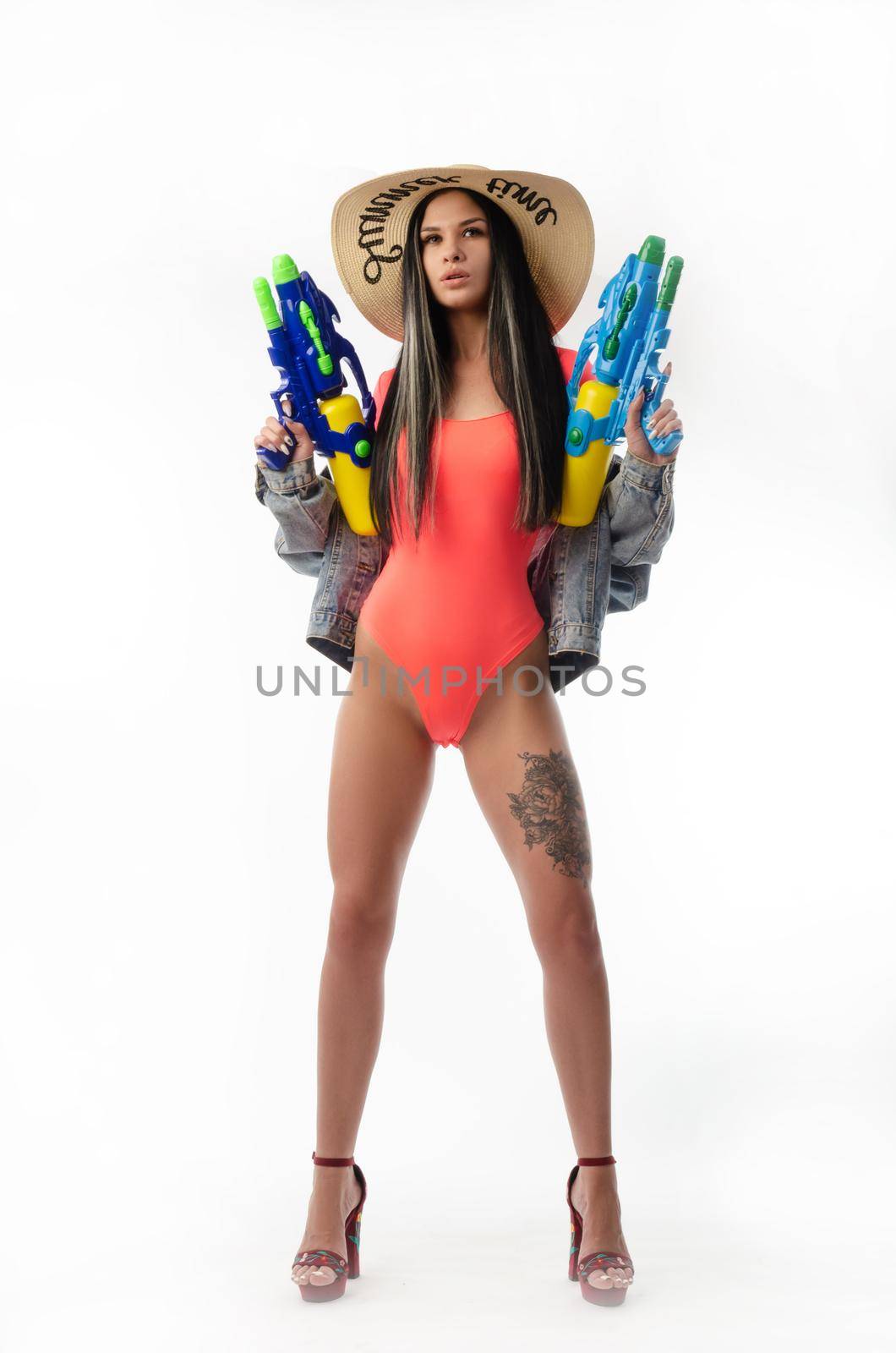 brunette girl with a water gun in summer clothes, slim and sexy isolated on a white background
