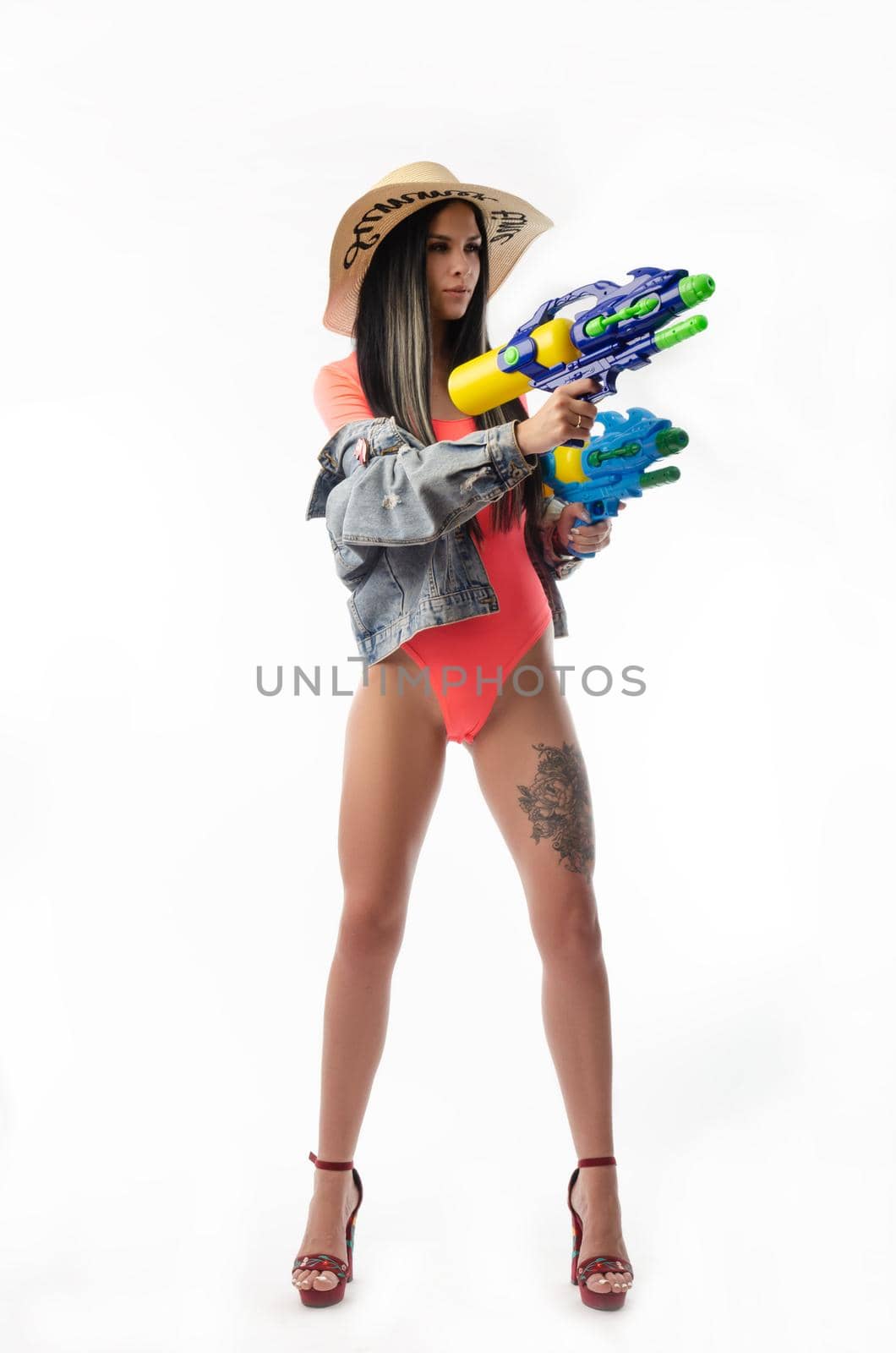 brunette girl with a water gun in summer clothes, slim and sexy isolated on a white background