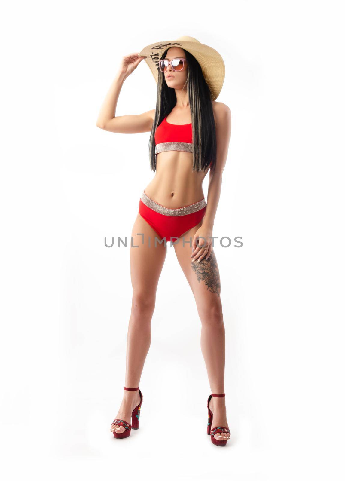 the brunette in a red swimsuit, slim and sexy in a summer hat isolated on a white background