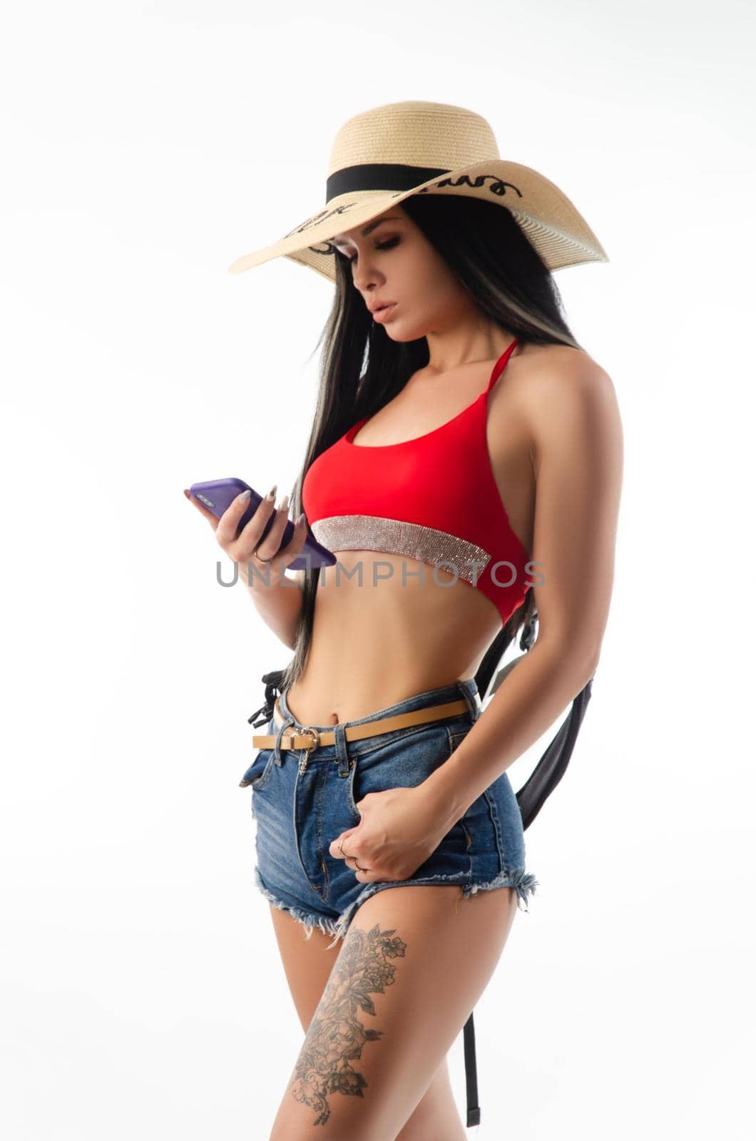 the brunette in a hat in summer clothes slim and sexy with a phone isolated on a white background