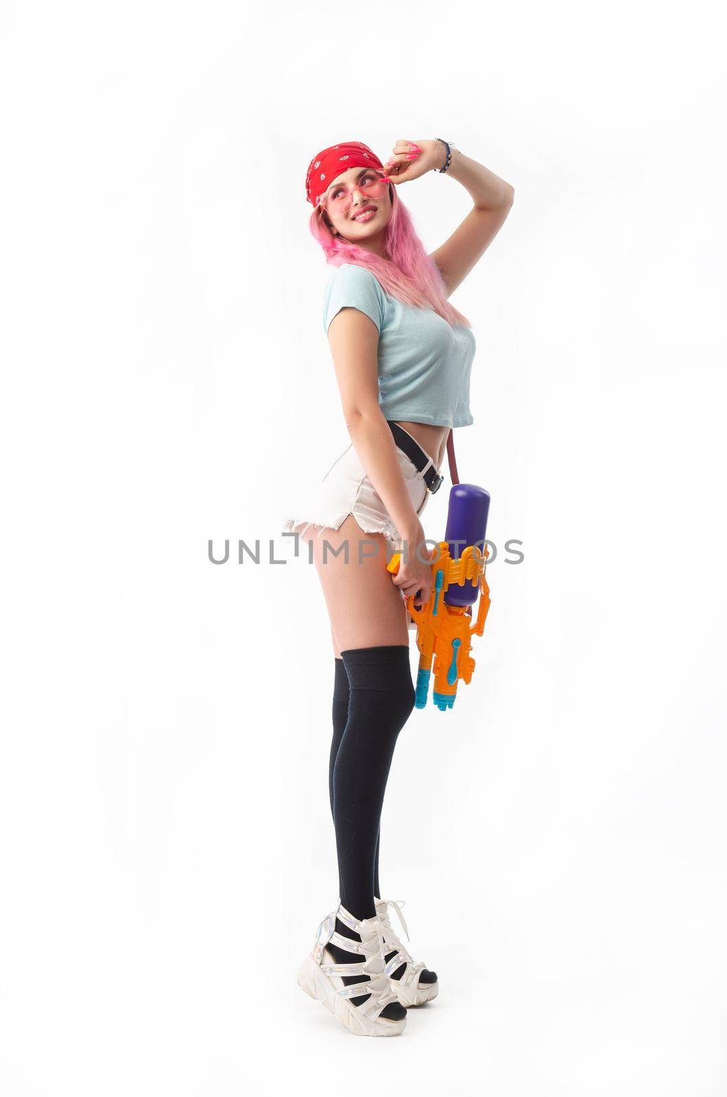 girl with a water gun in summer clothes, slim and sexy isolated on a white background