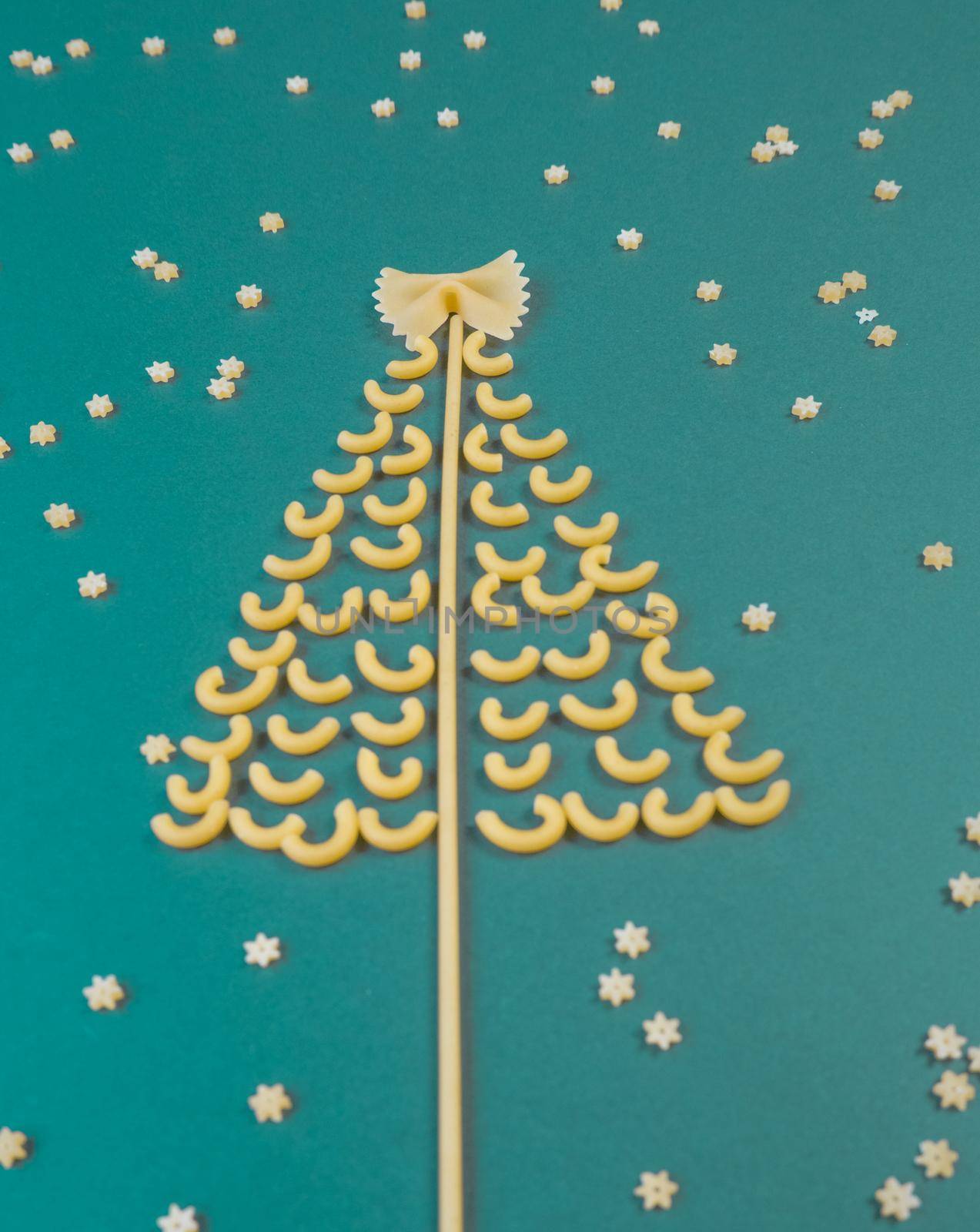 Christmas tree made from pasta, stars on paper green background.