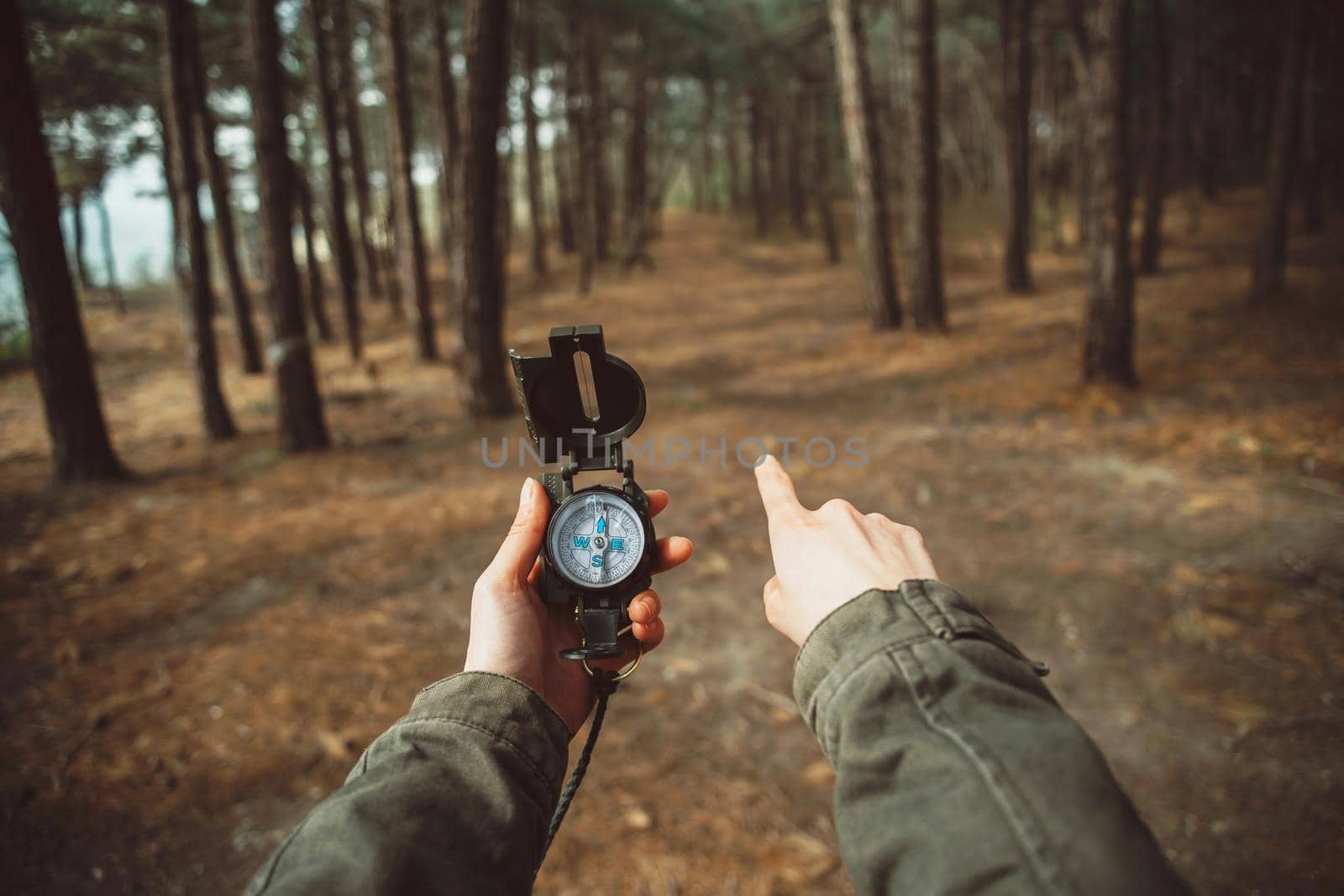 Traveler woman holding a compass and pointing direction in the forest. Close-up. Point of view shot