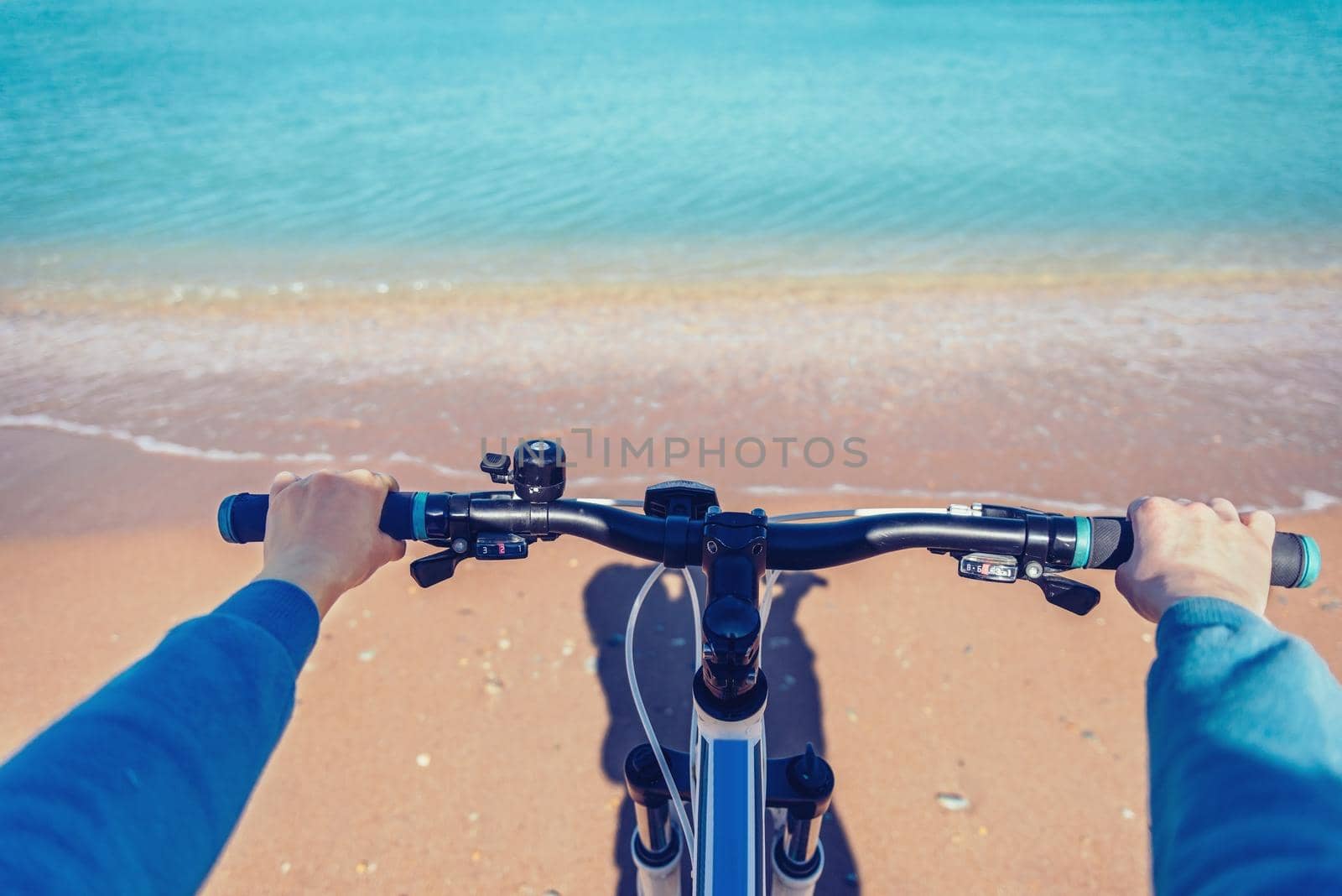 Woman holding handlebar of bicycle on beach in summer. Point of view shot
