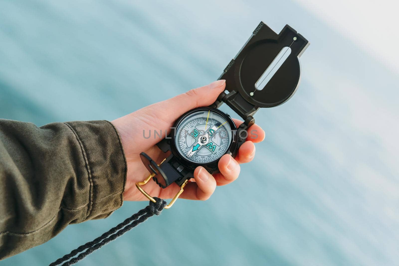 Hiker searching direction with a compass on background of sea. Point of view shot