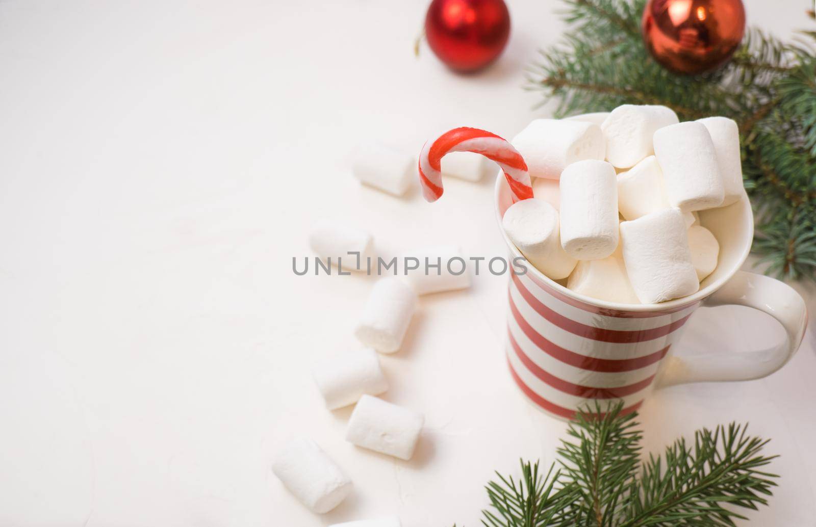 Traditional hot chocolate with marshmallows and lollipops on a white textured background. Christmas drink theme