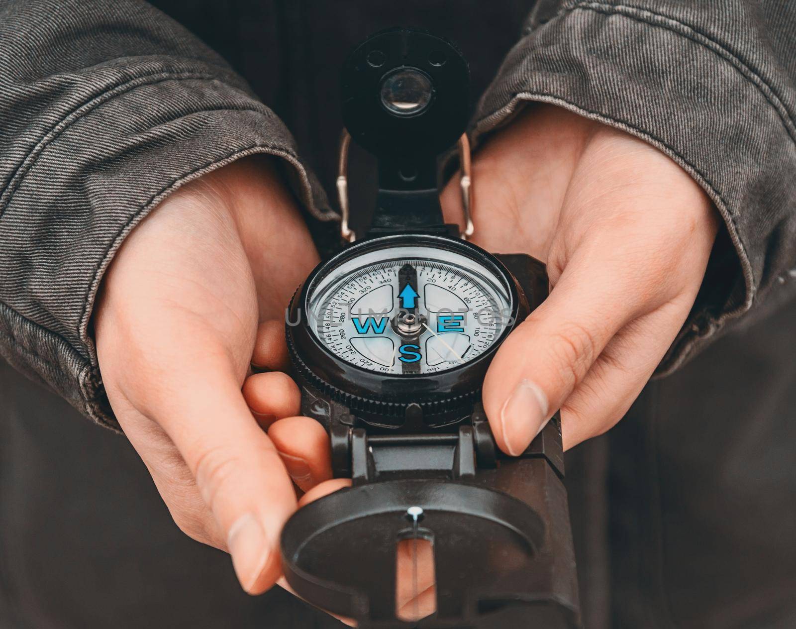 Hiker woman holding a compass on nature. Close-up image