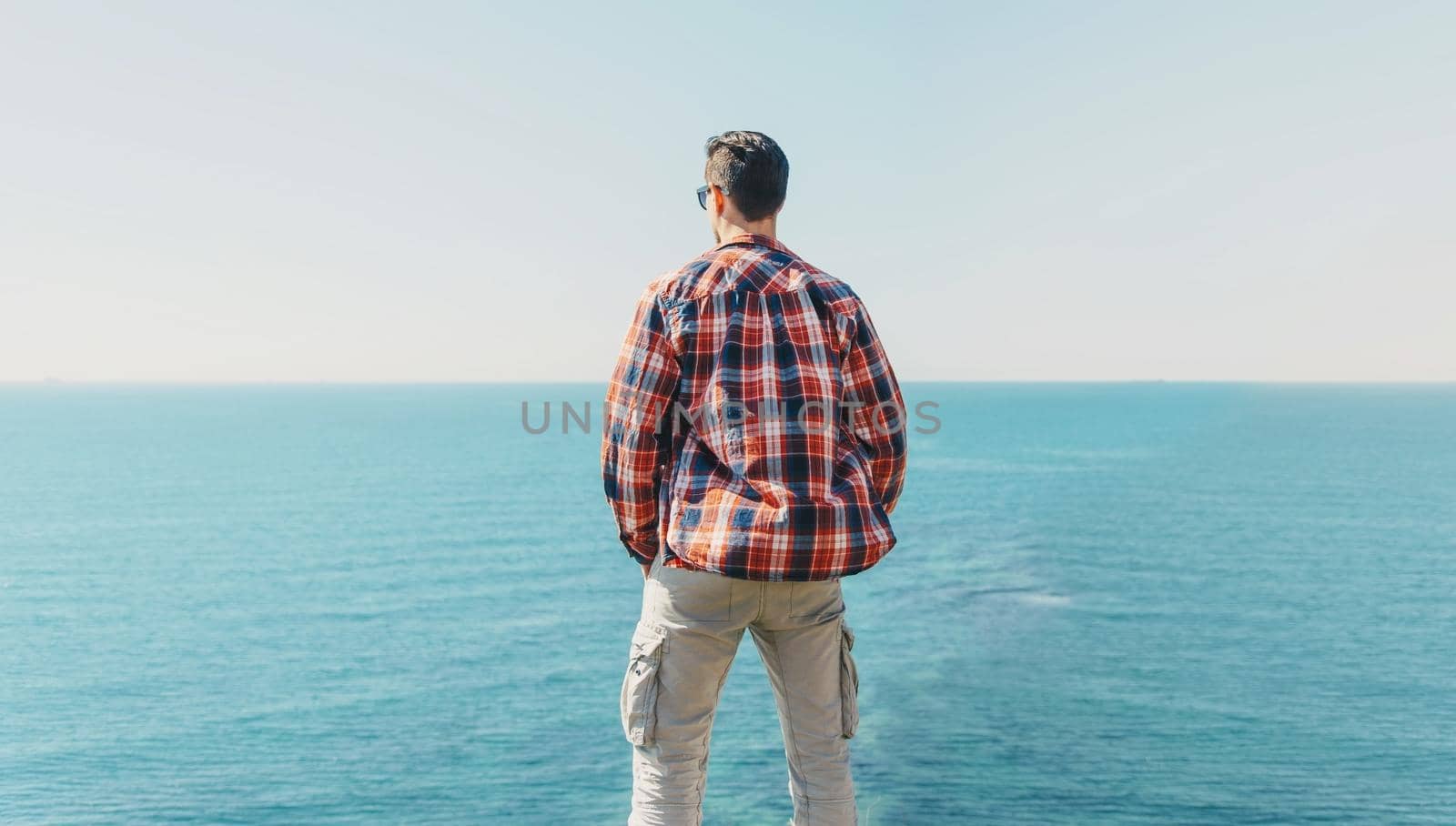 Young man enjoying view of sea in summer, rear view