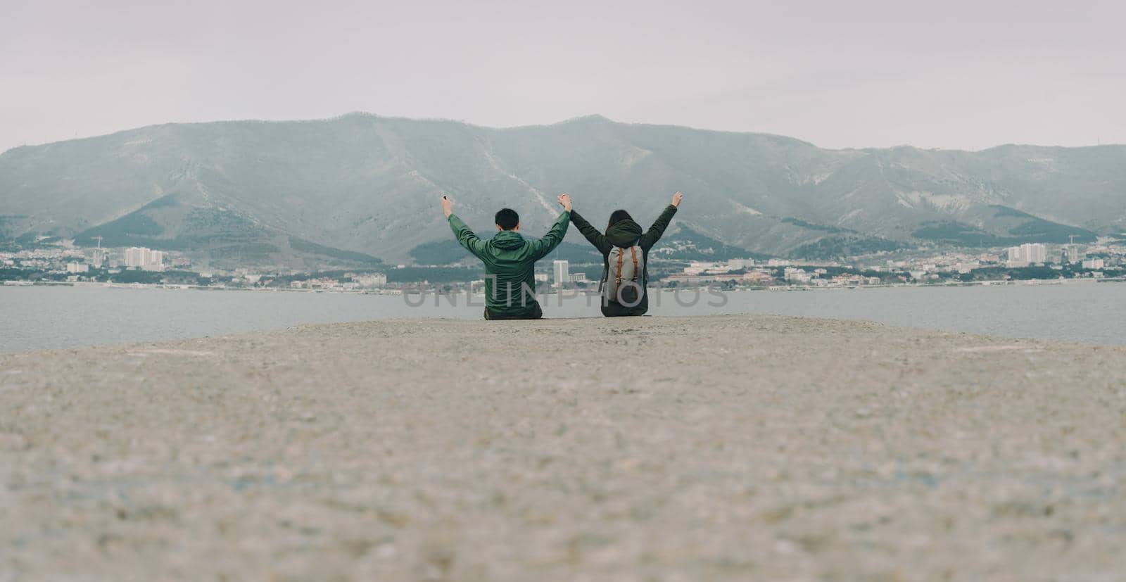 Happy loving couple sitting on pier by alexAleksei