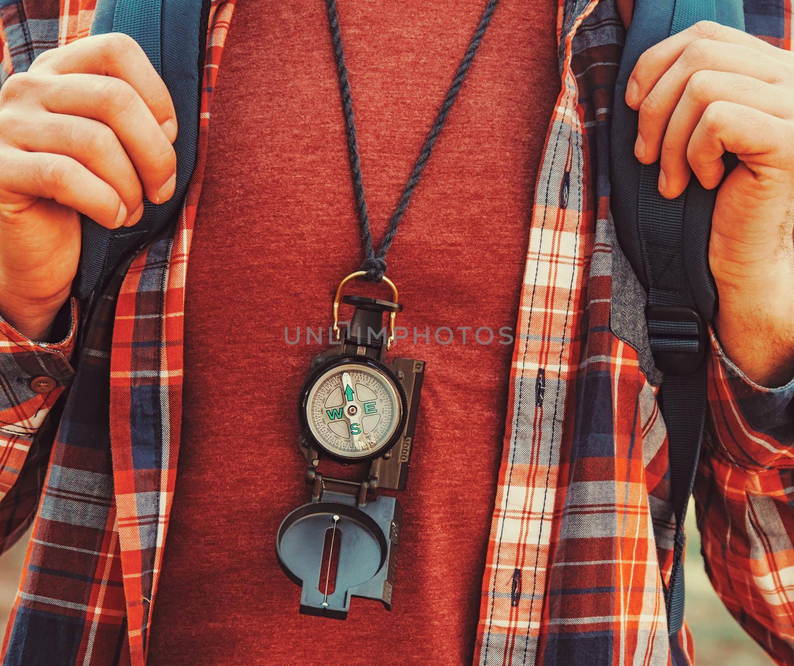 Traveler young man with backpack and compass walking in forest. Close-up