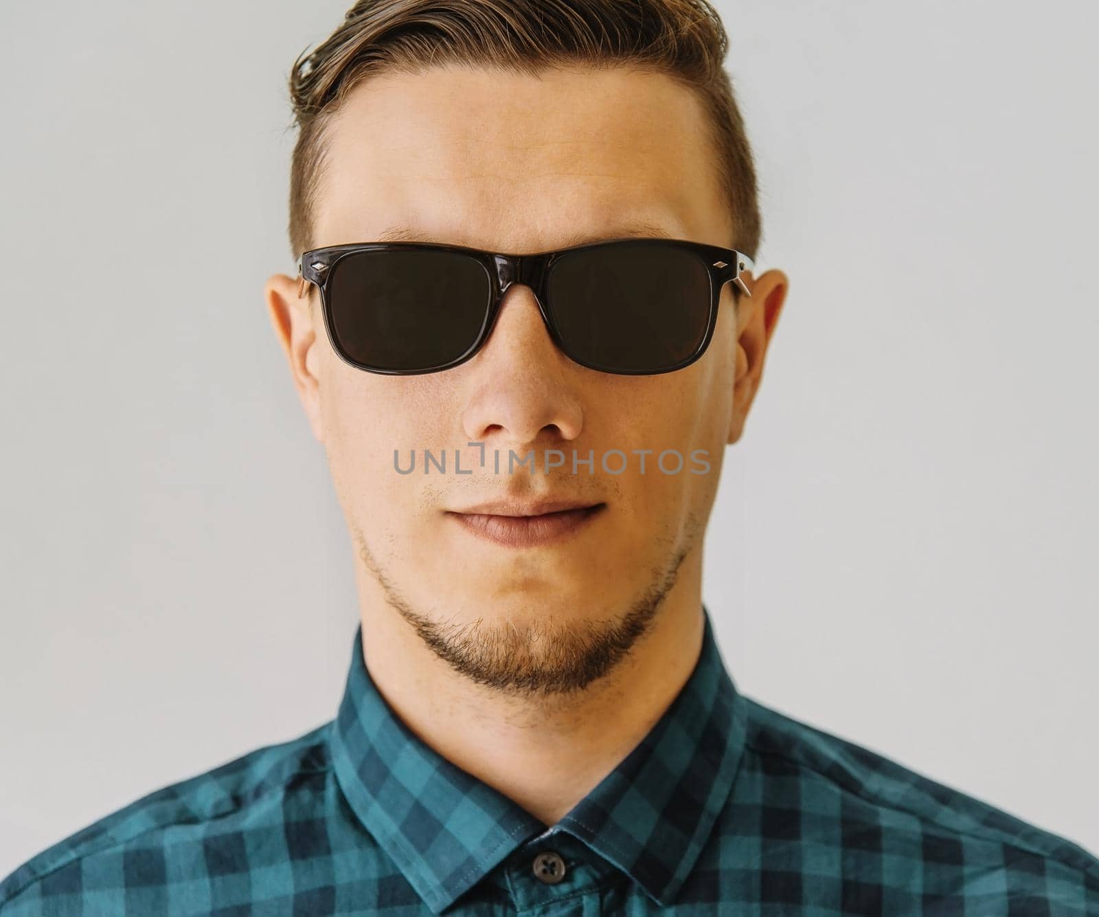 Portrait of handsome young brunet man in sunglasses and plaid shirt