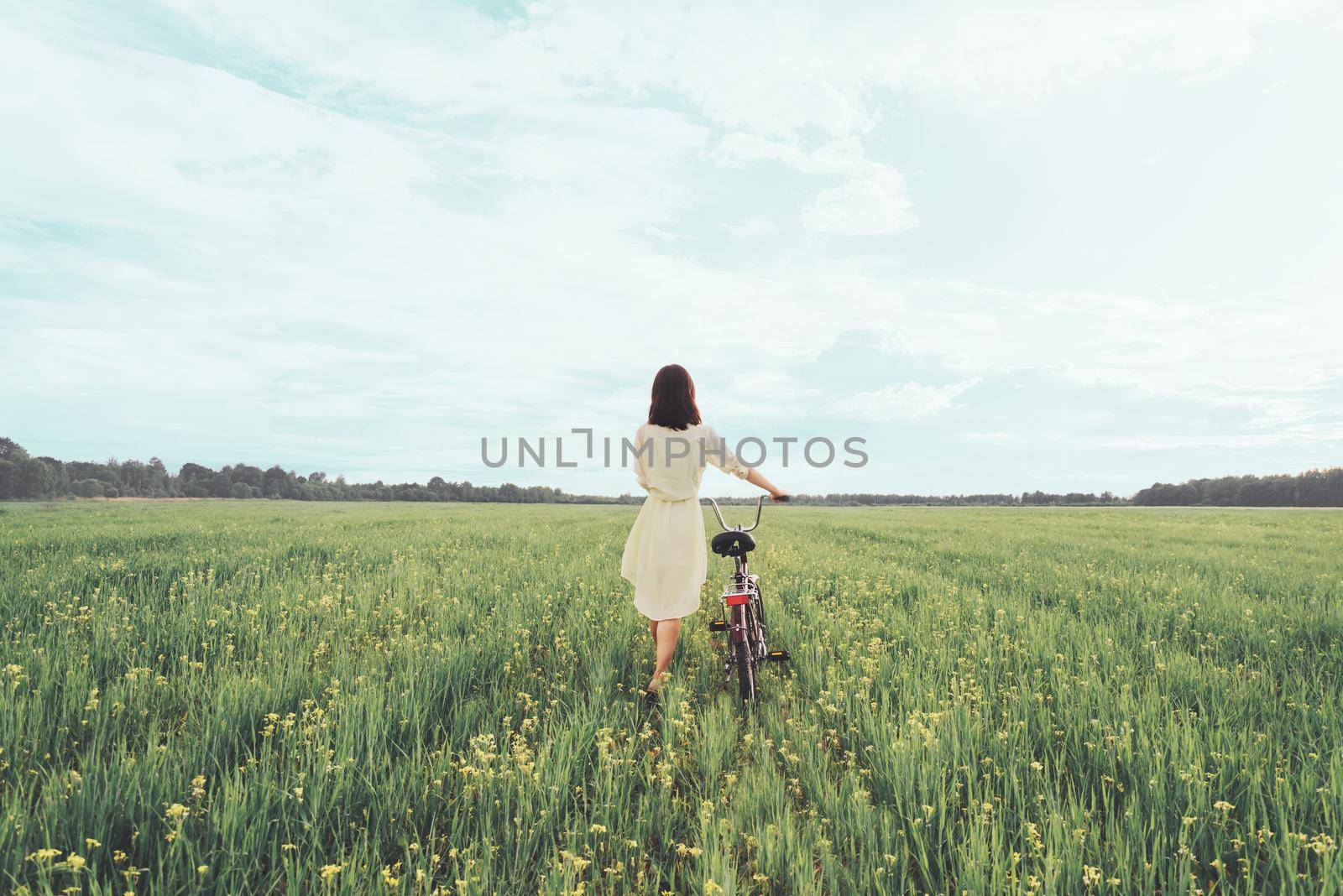 Girl walking with bicycle in summer by alexAleksei