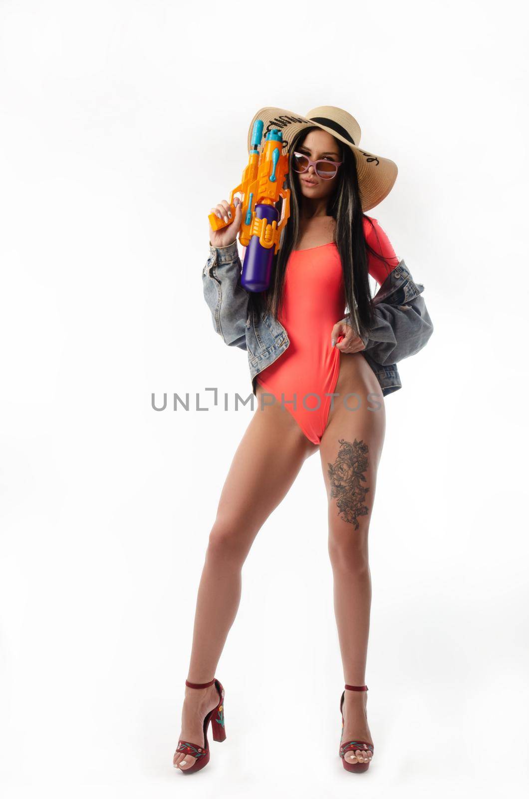the brunette with a water gun in summer clothes, slim and sexy in a swimsuit isolated on a white background