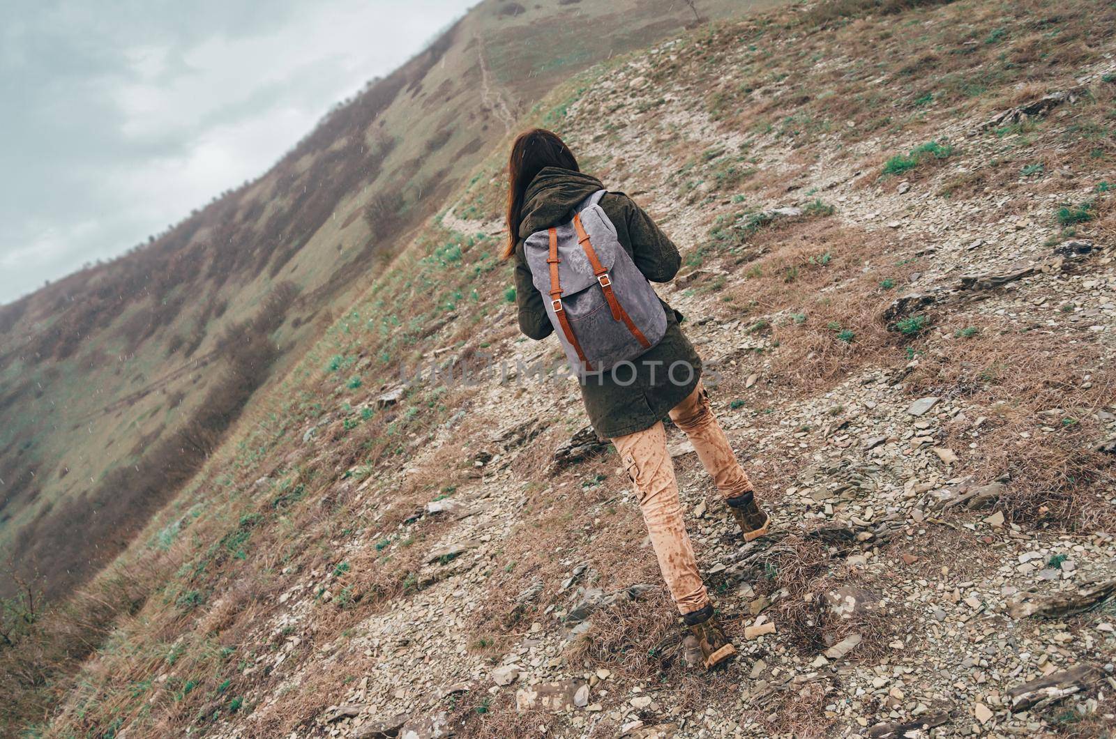 Hiker young woman with backpack walking up mountain