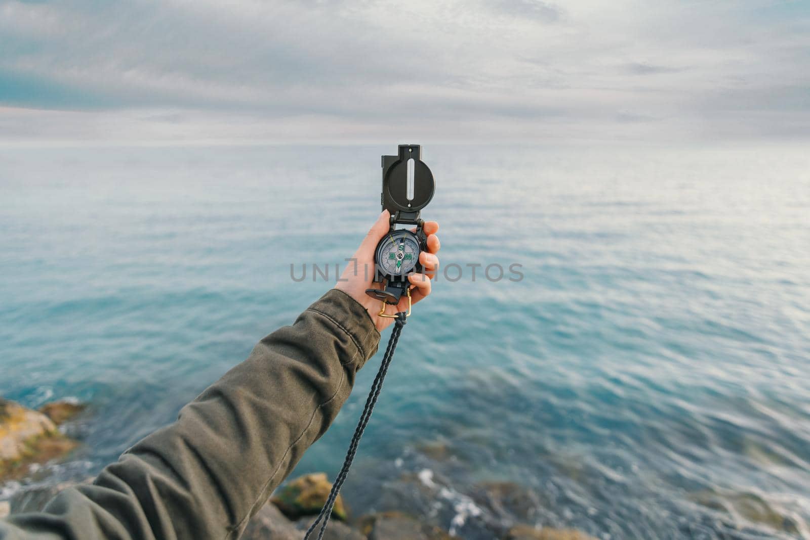 Traveler searching direction with a compass on coast near the sea in summer. Point of view