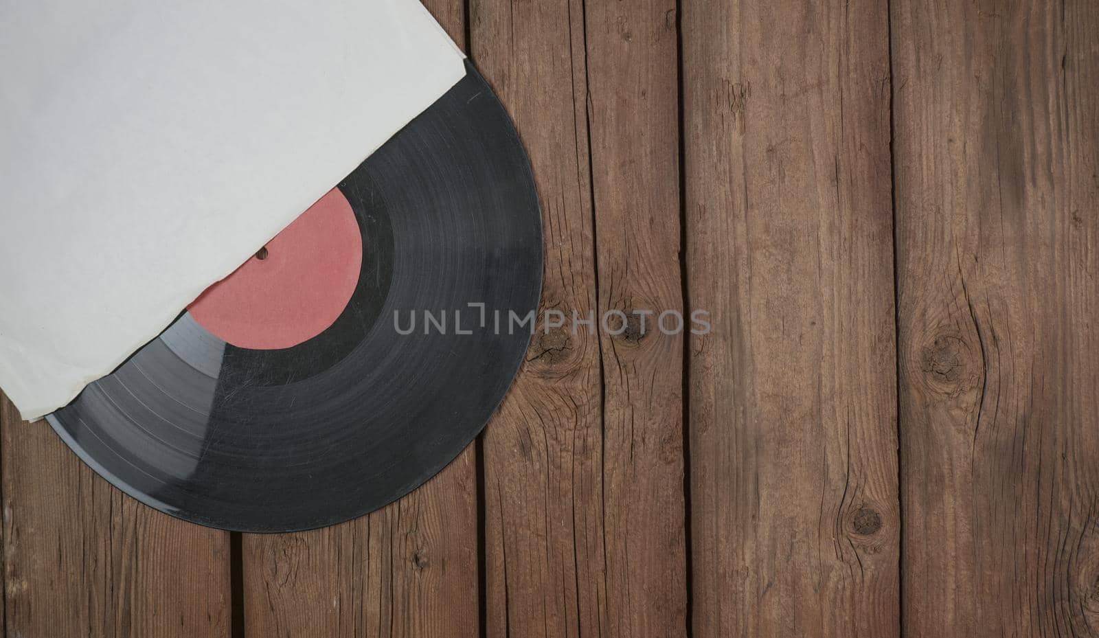 Old vinyl record in paper case on wooden rustic background