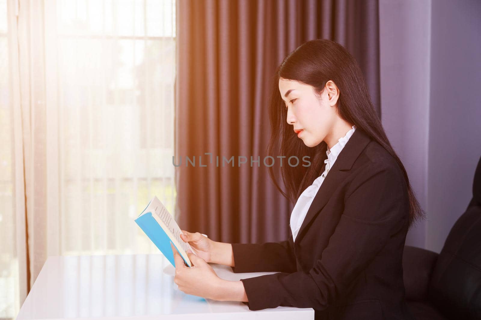 young business woman sitting at the desk and reading a book