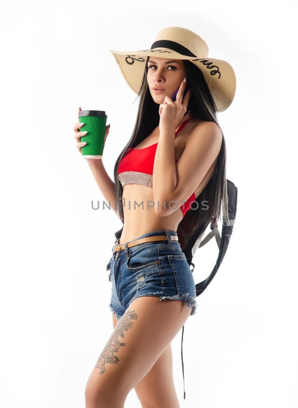 the brunette in a hat in summer clothes slim and sexy with a phone isolated on a white background