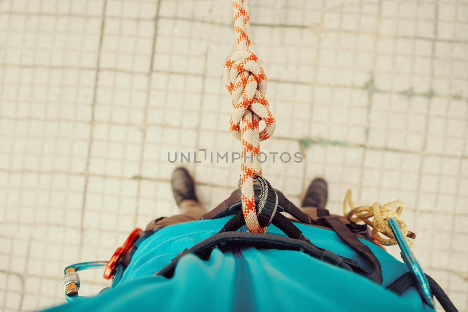 Climber man standing in harness with rope and knot Eight. Point of view shot. Top view
