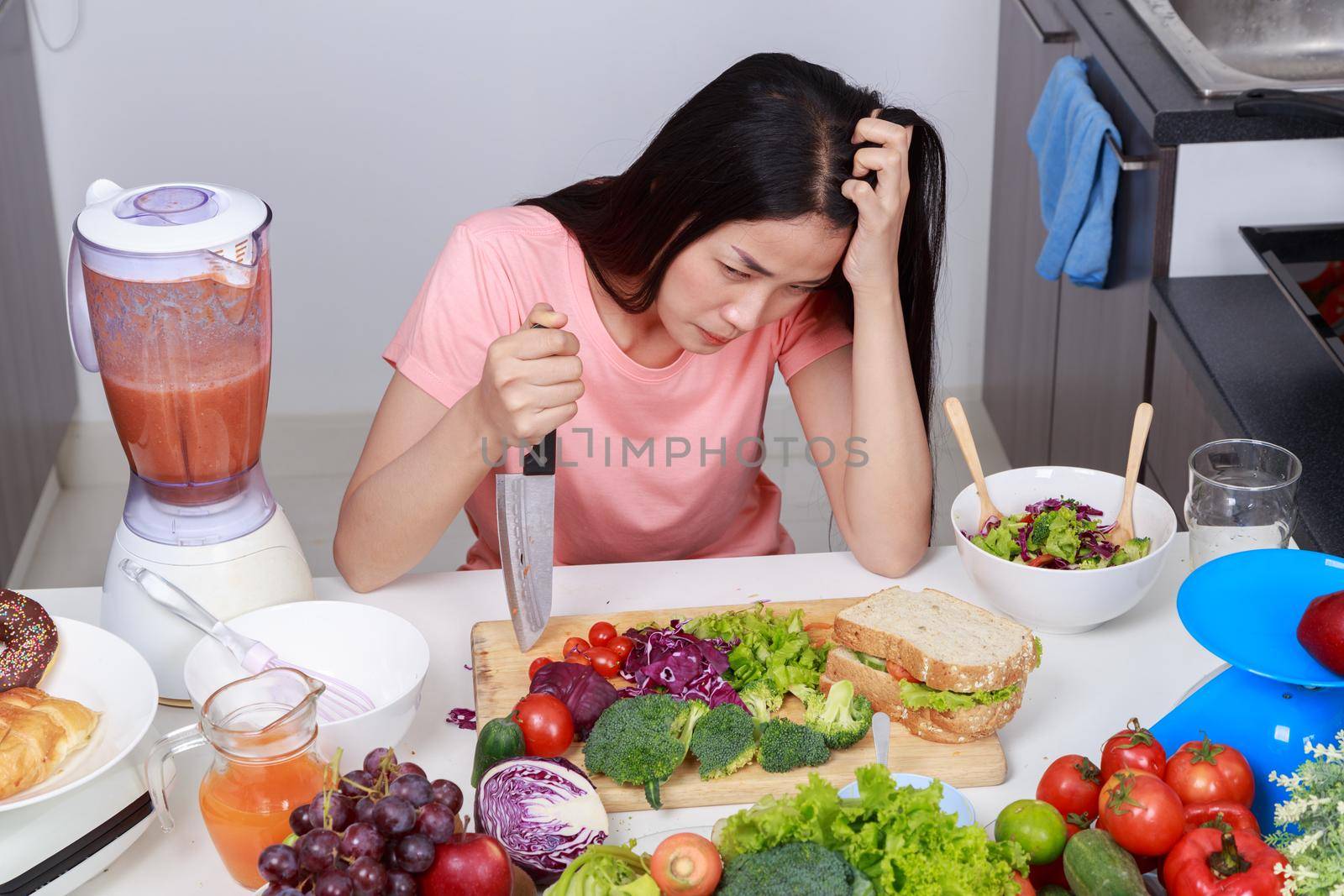 depressed young woman cooking with knife in kitchen room