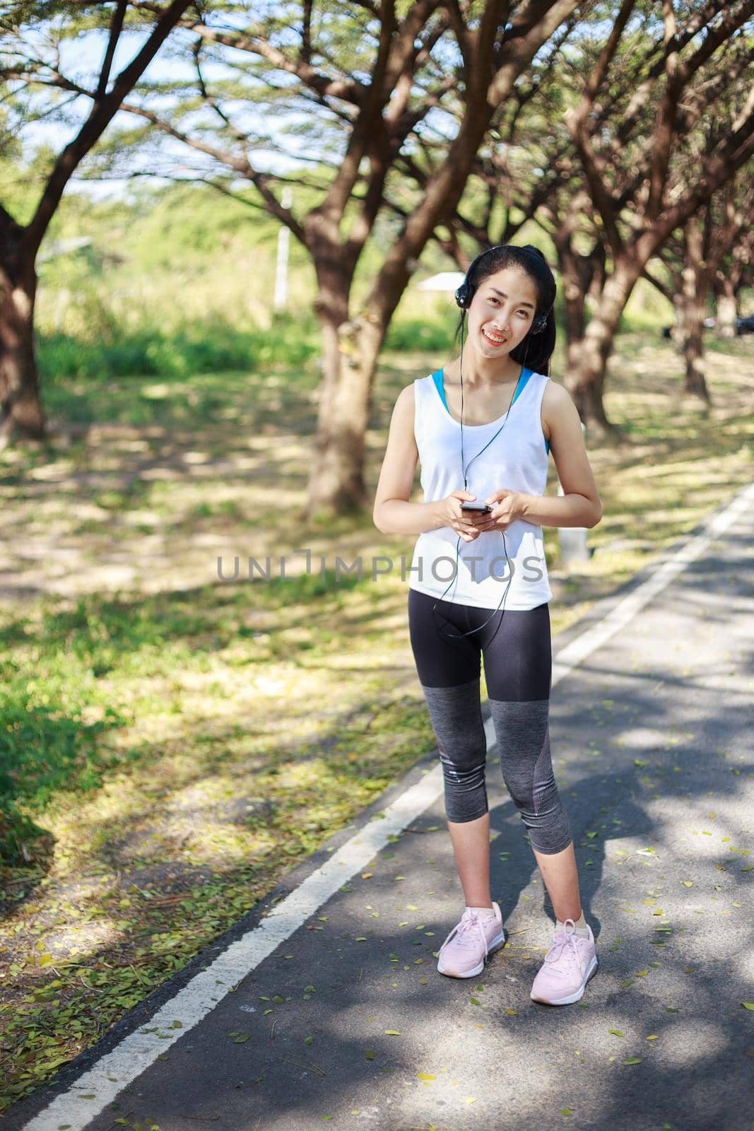 young sporty woman using smartphone with headphone in the park