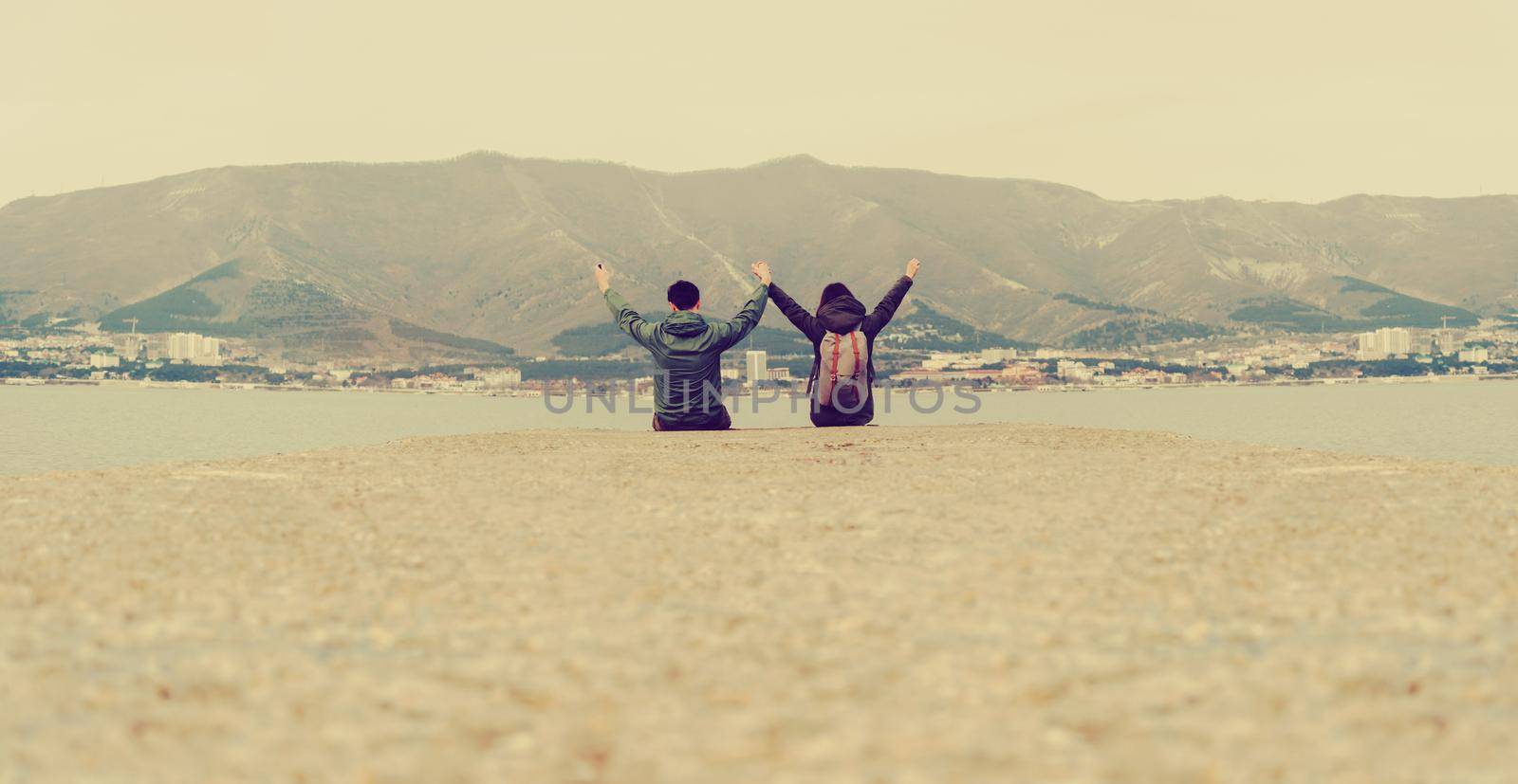 Happy loving couple sitting on pier by alexAleksei
