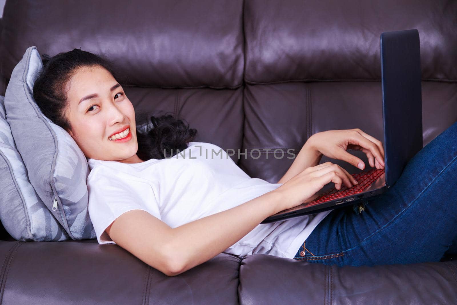 young beautiful woman using a laptop computer on sofa in living room at home