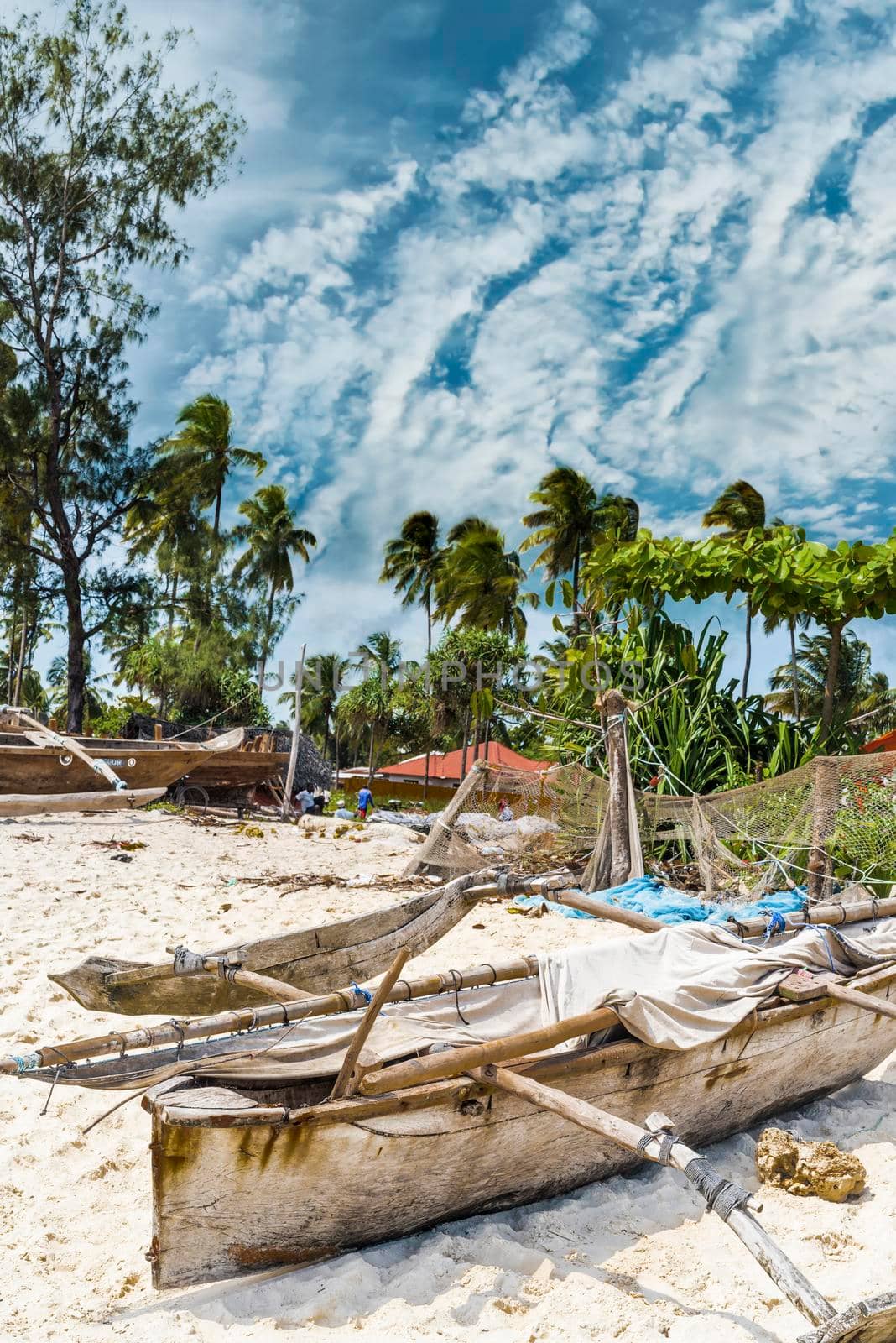 old wooden fishing boat with oar on african beach near a village