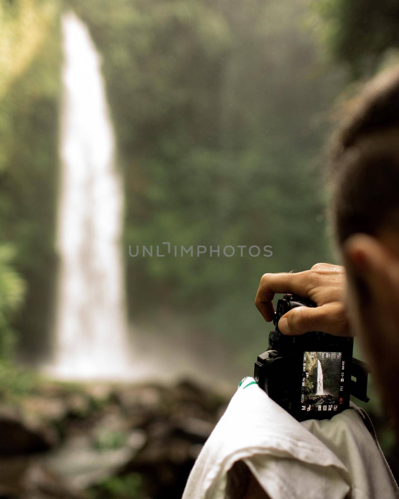 video operator filming a waterfall. by Alexzhilkin