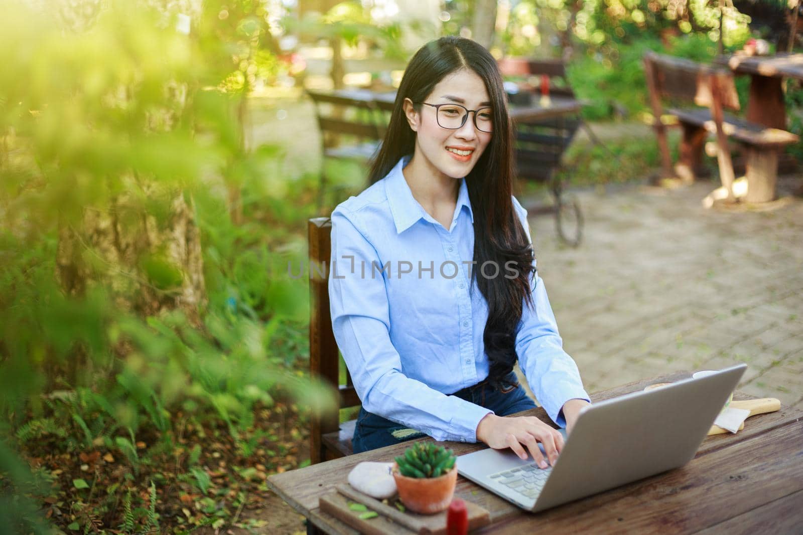 young woman using laptop and drinking coffee in the garden
