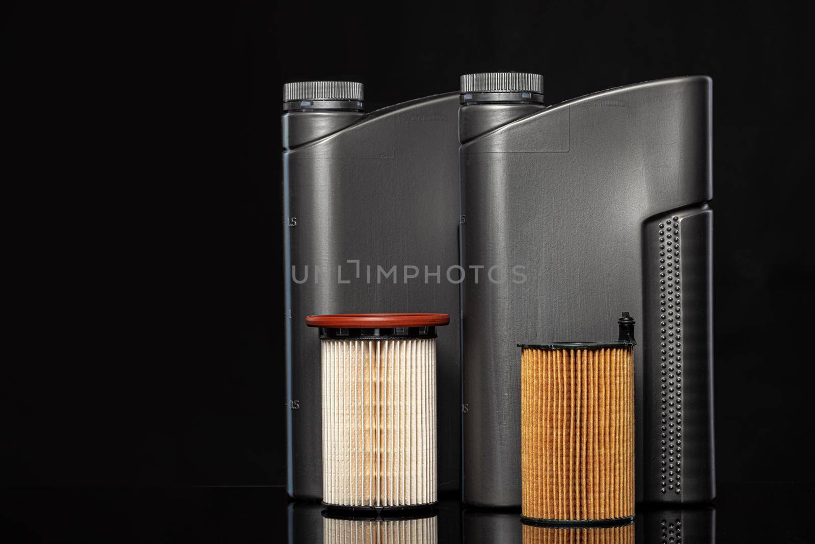 Car oil filters and motor oil can on dark background, close up.